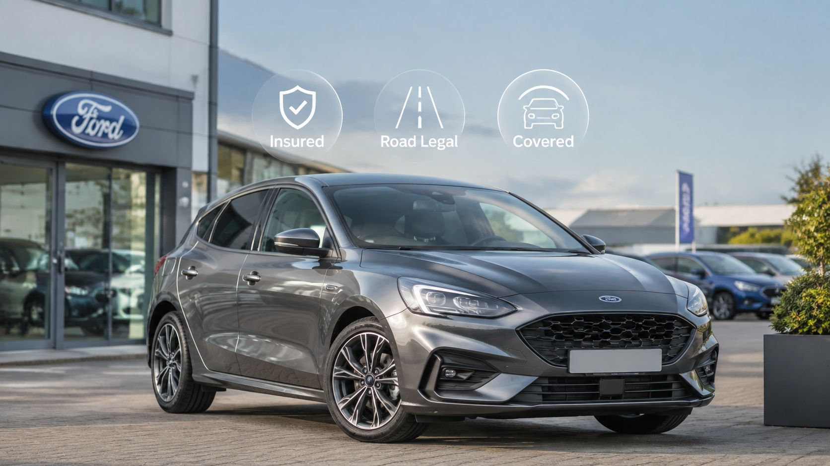 A modern grey Ford hatchback parked outside a Ford dealership, featuring insurance, road legal, and coverage icons.